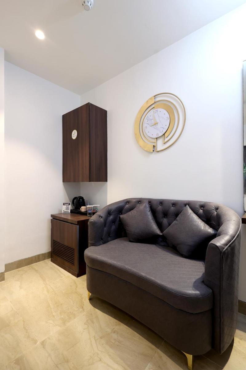 a couch in a living room with a clock on the wall at MyOtel - Santacruz in Mumbai