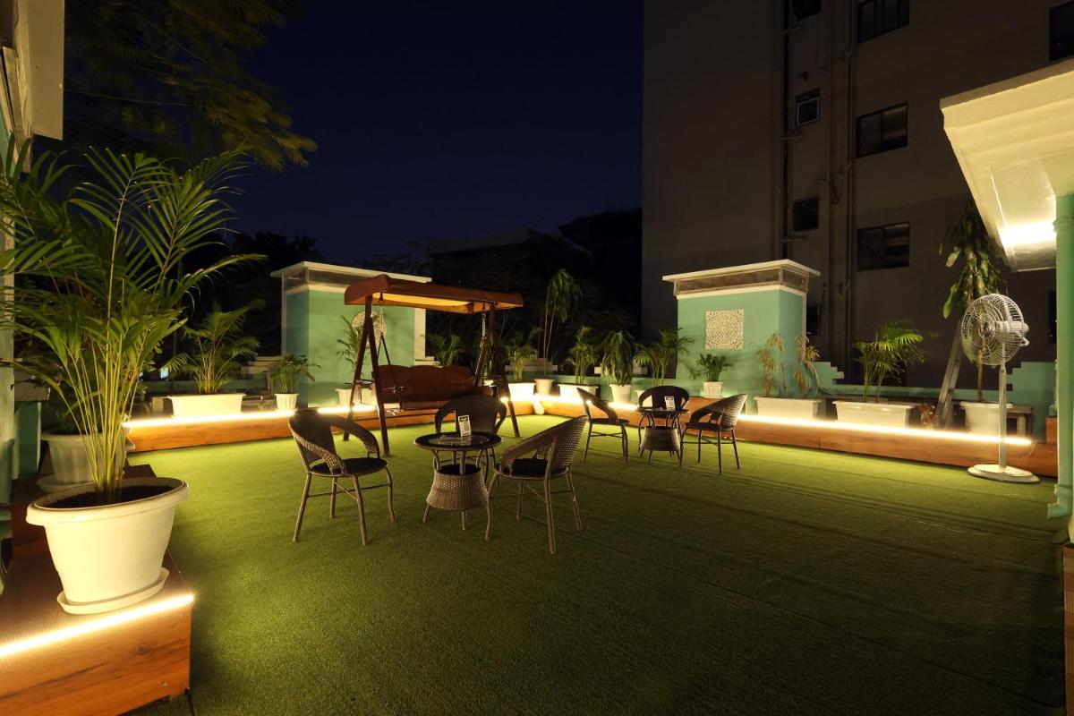 a patio with chairs and tables on a lawn at night at MyOtel - Santacruz in Mumbai