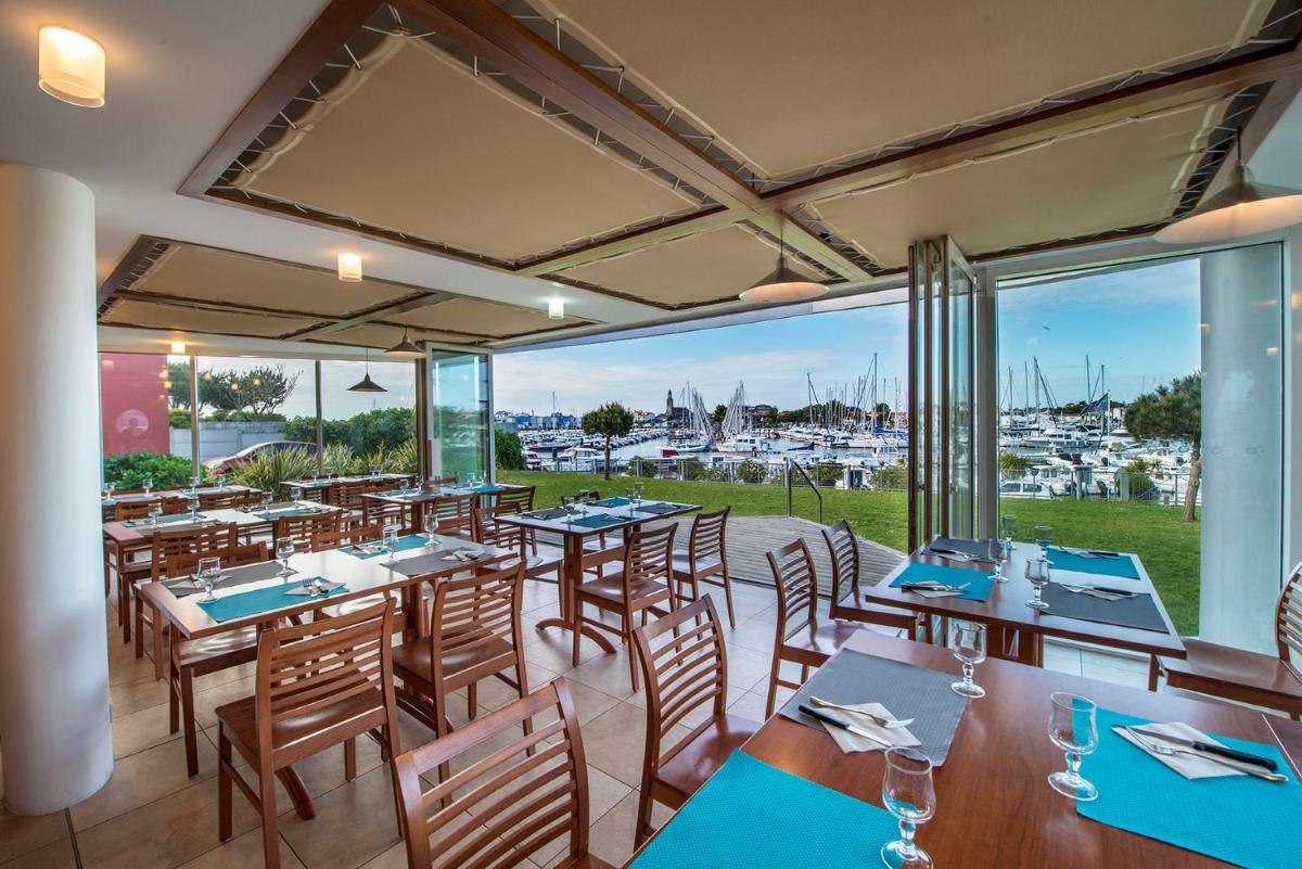 - un restaurant avec des tables et des chaises et une vue sur le port dans l'établissement TERNELIA Le Vent Du Large, à Saint-Gilles-Croix-de-Vie