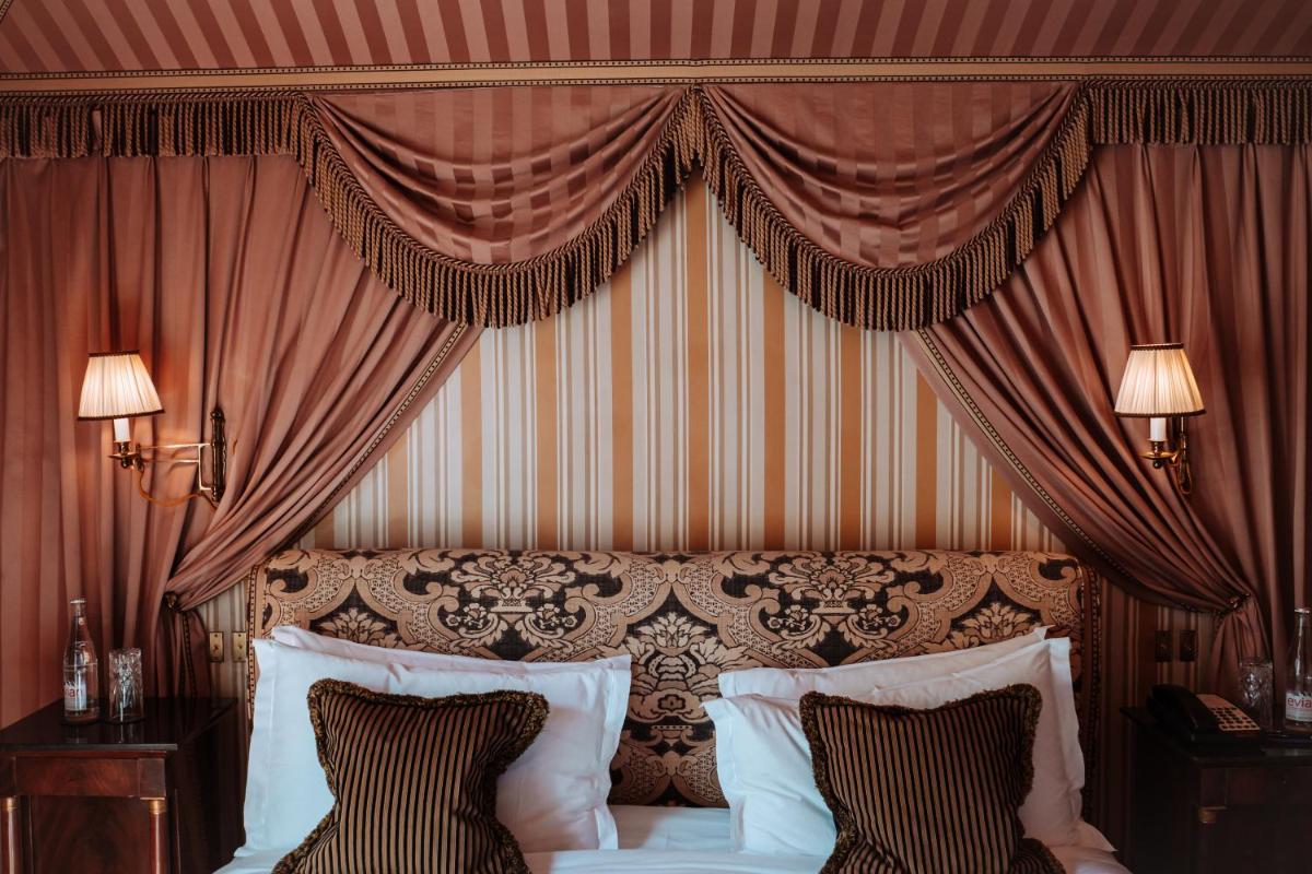 - une chambre avec un grand lit et des rideaux rouges dans l'établissement L'Hôtel, à Paris