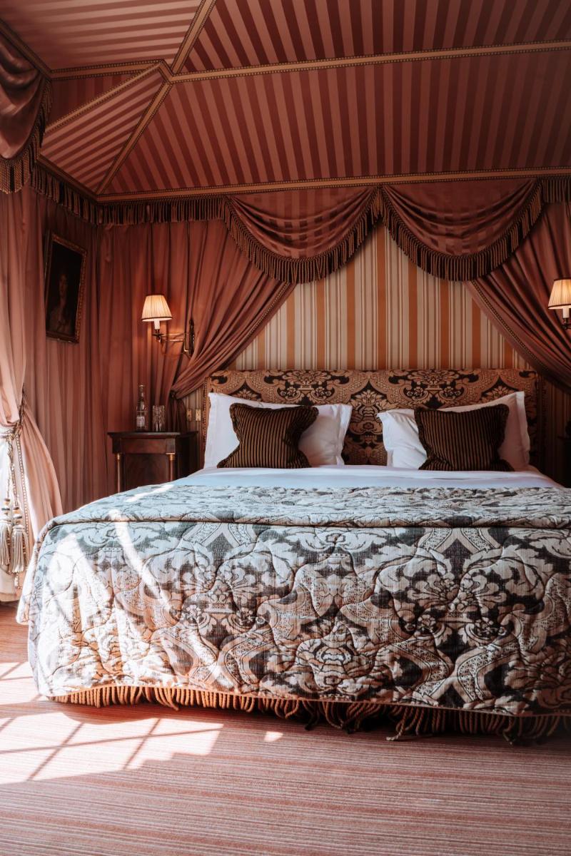 une chambre avec un grand lit à baldaquin dans l'établissement L'Hôtel, à Paris