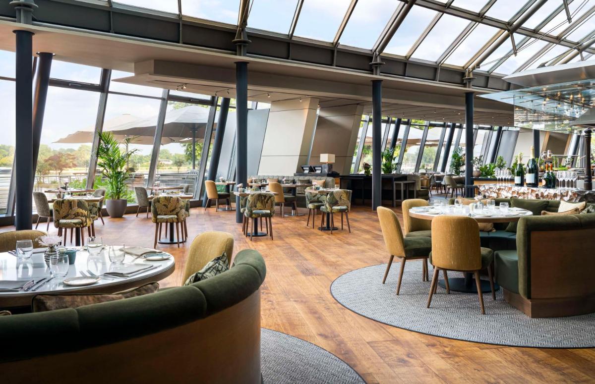 ein Restaurant mit Tischen und Stühlen und Fenstern in der Unterkunft Hyatt Regency Mainz in Mainz