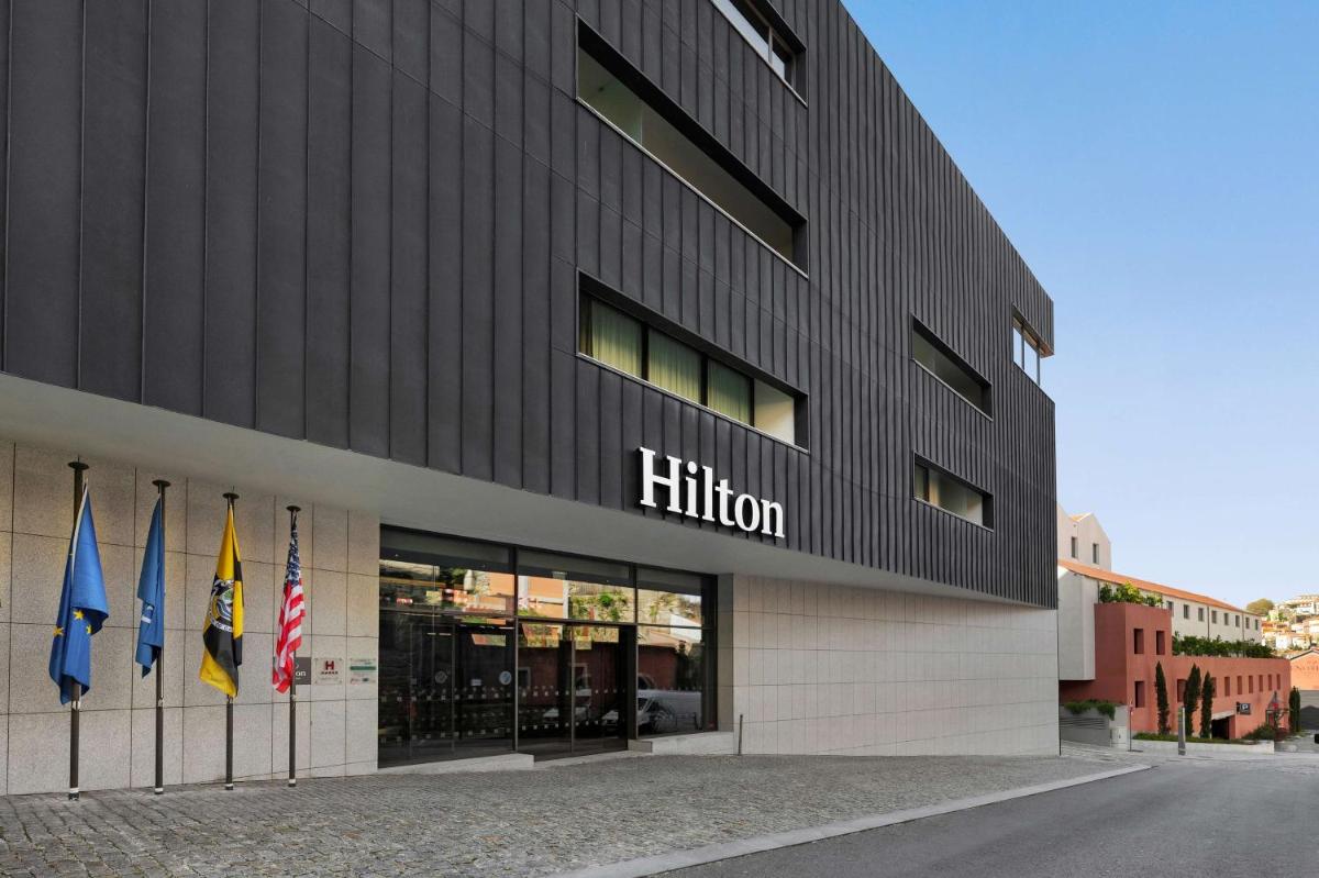 um prédio com três bandeiras na frente dele em Hilton Porto Gaia em Vila Nova de Gaia