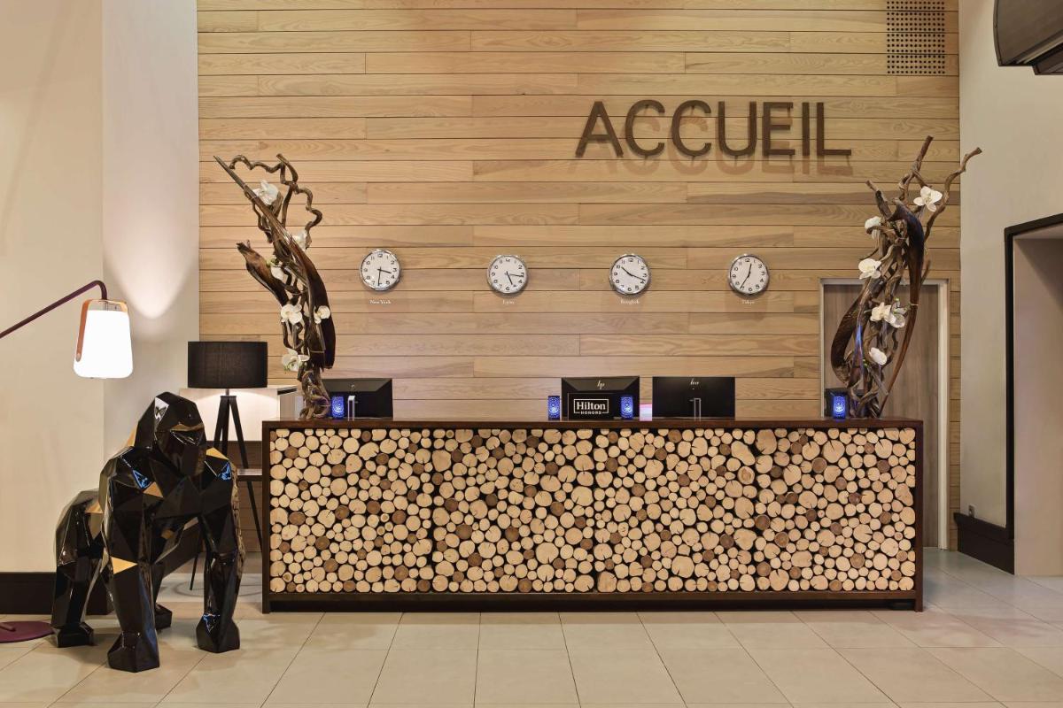 un hall d'entrée avec un bureau de réception avec des horloges au mur dans l'établissement DoubleTree by Hilton Lyon Eurexpo & Spa, à Saint-Priest