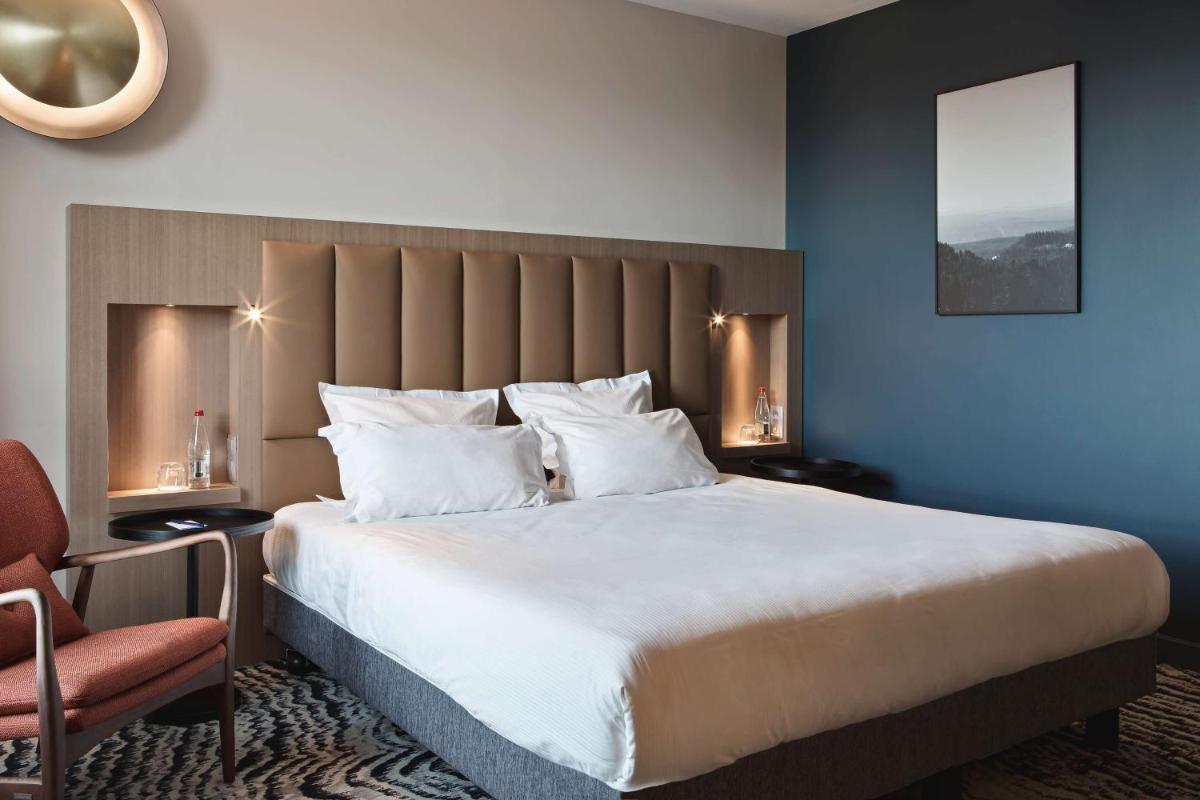 une chambre avec un grand lit et une chaise dans l'établissement DoubleTree by Hilton Lyon Eurexpo & Spa, à Saint-Priest