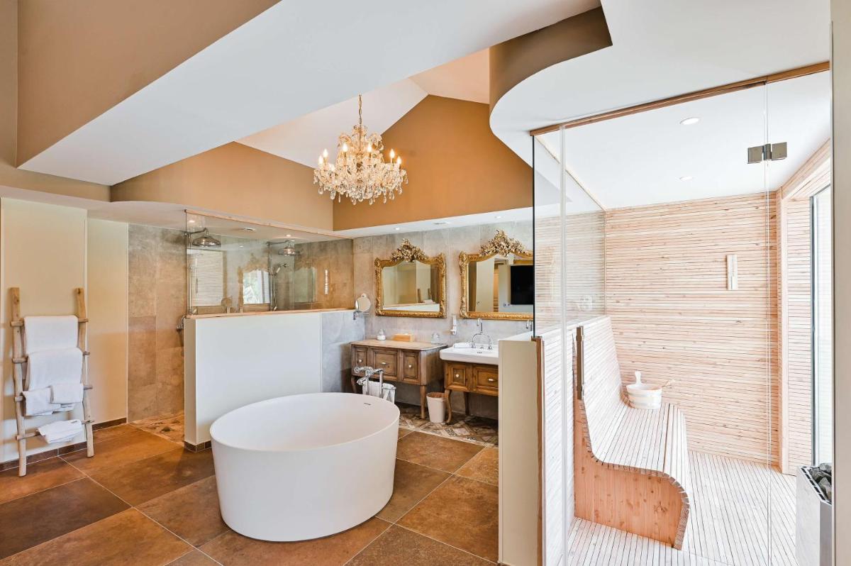 une salle de bain avec une grande baignoire et un lavabo dans l'établissement Le Hameau Des Pesquiers Ecolodge & Spa, Curio Collection By Hilton, à Hyères