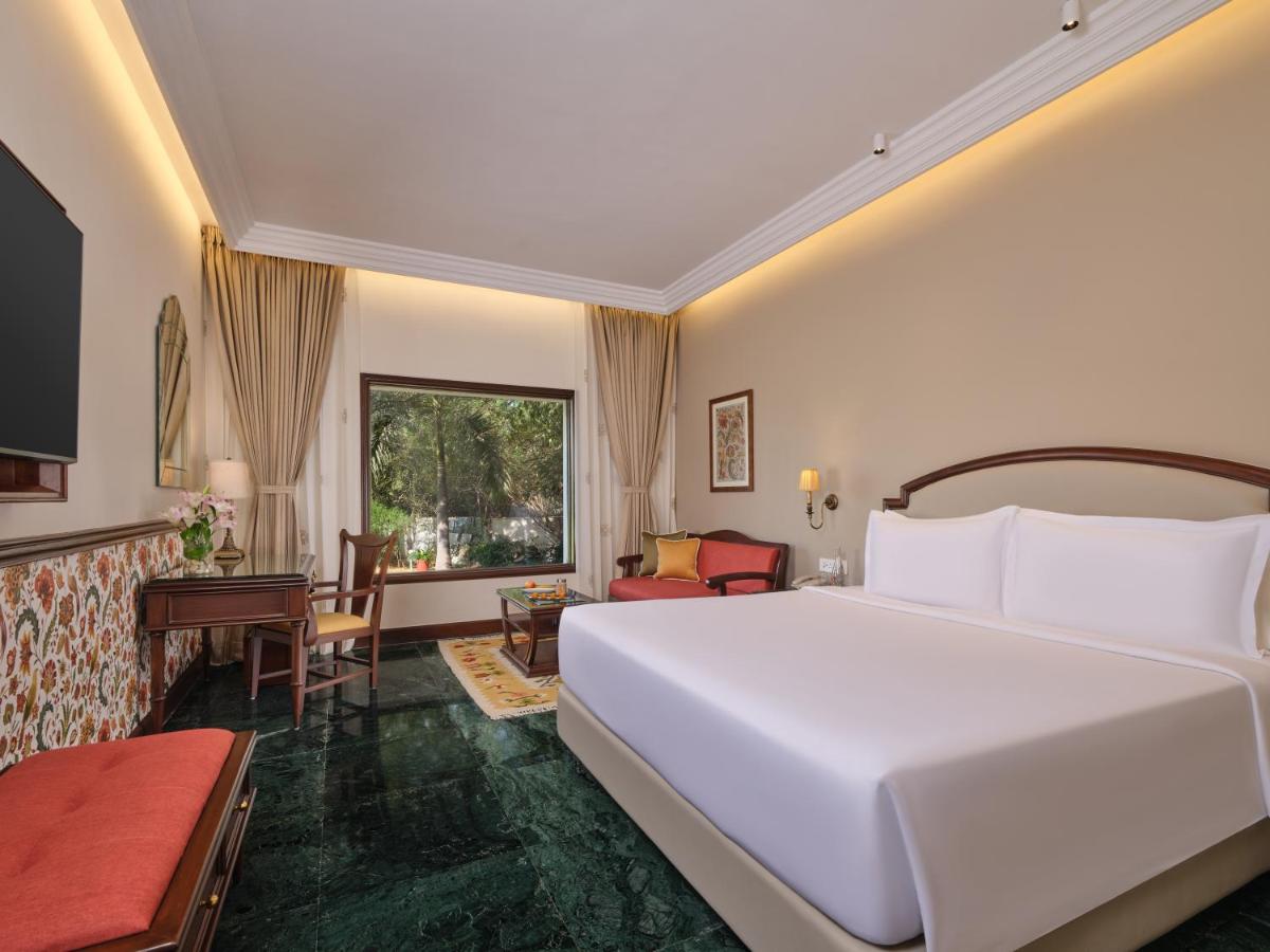 a bedroom with a large white bed and a desk at The Ummed Ahmedabad Airport in Ahmedabad