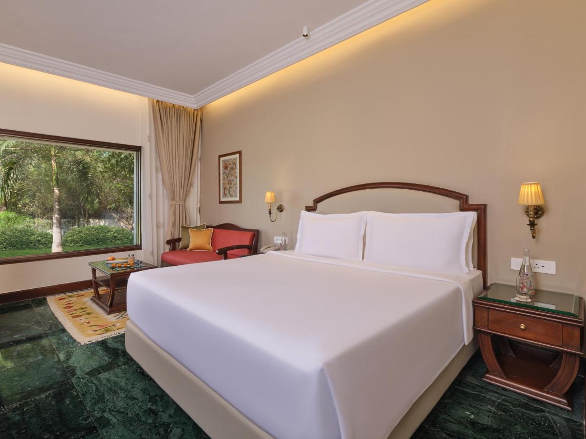 a bedroom with a large white bed and a window at The Ummed Ahmedabad Airport in Ahmedabad