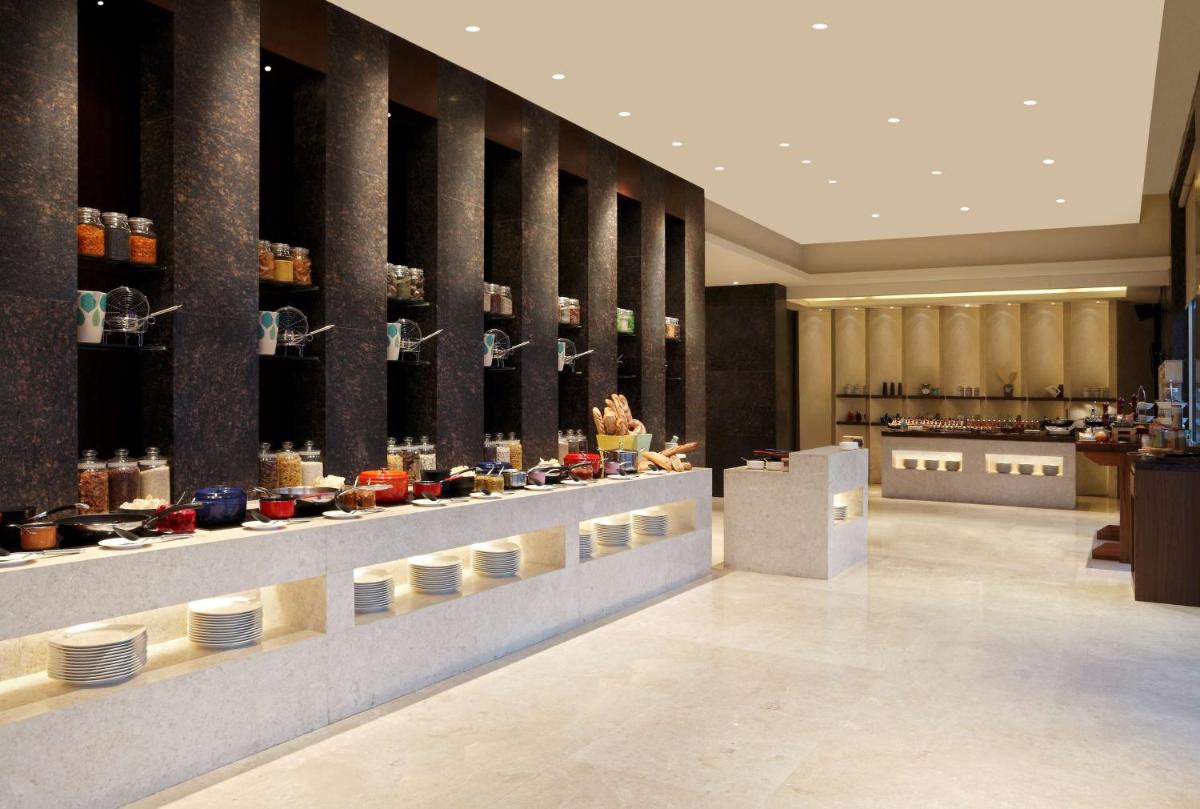 a restaurant with a counter with plates on display at DoubleTree by Hilton-Pune Chinchwad in Pune