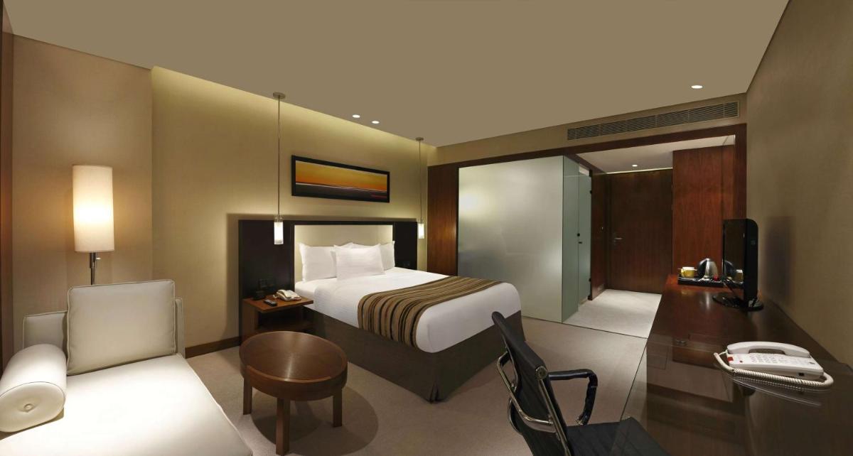 a hotel room with a bed and a desk and a chair at DoubleTree by Hilton-Pune Chinchwad in Pune