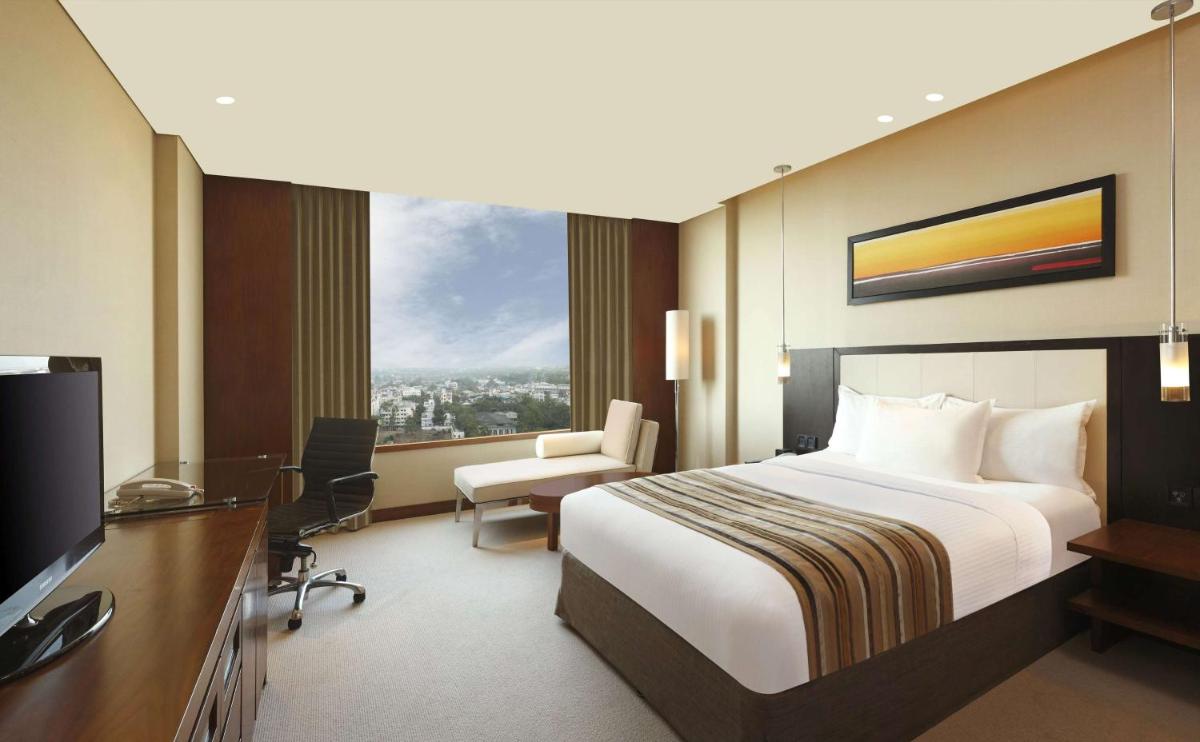 a hotel room with a bed and a desk and a television at DoubleTree by Hilton-Pune Chinchwad in Pune