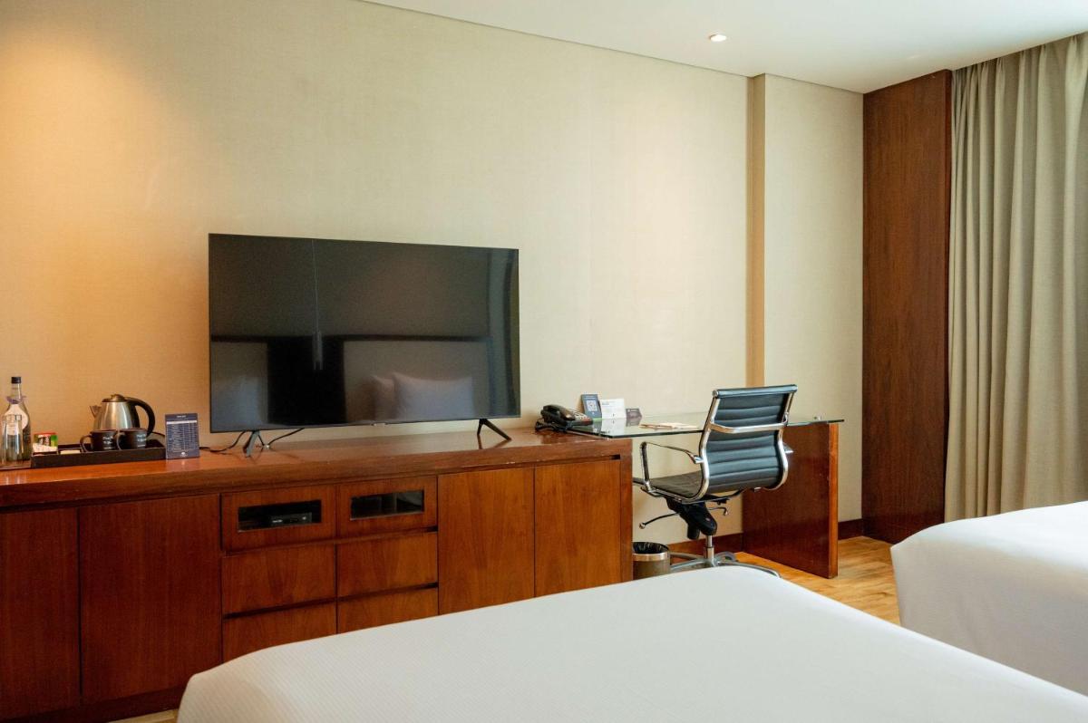 a hotel room with a television and a desk with a chair at DoubleTree by Hilton-Pune Chinchwad in Pune