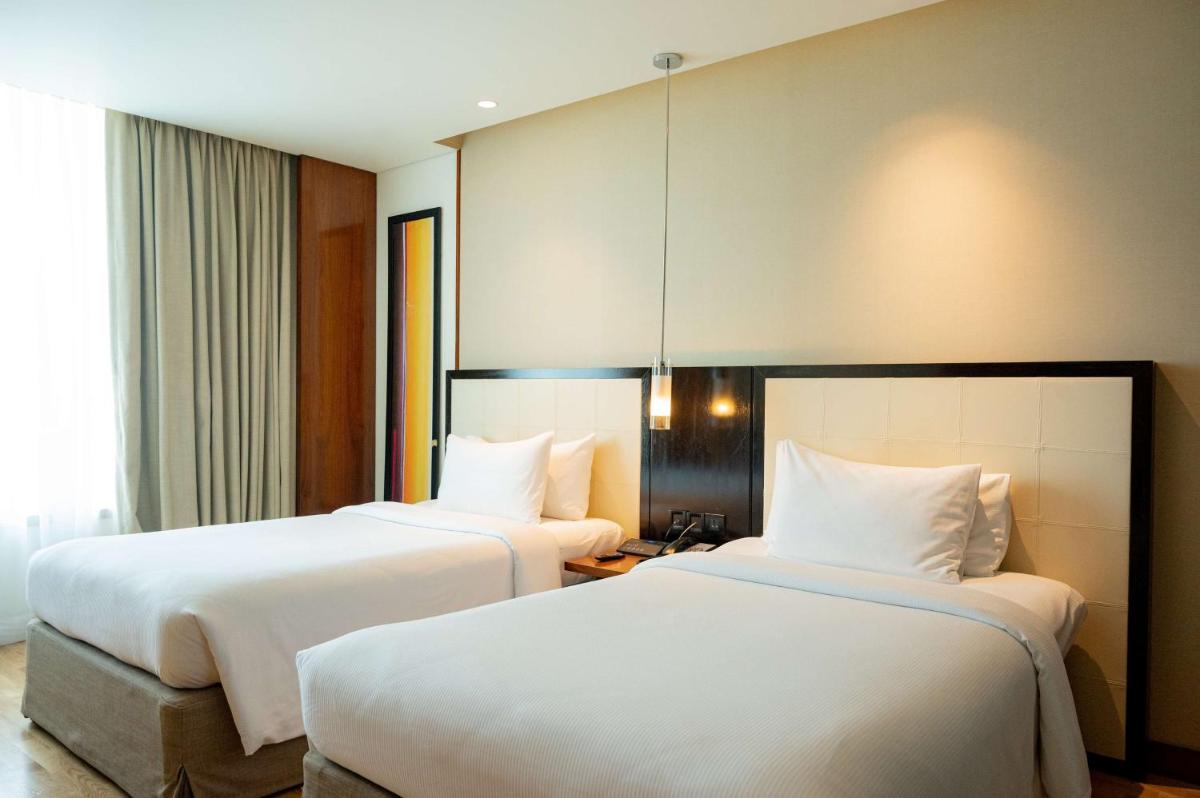 two beds in a hotel room with white sheets at DoubleTree by Hilton-Pune Chinchwad in Pune