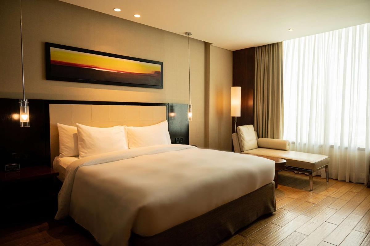 a hotel room with a large bed and a chair at DoubleTree by Hilton-Pune Chinchwad in Pune