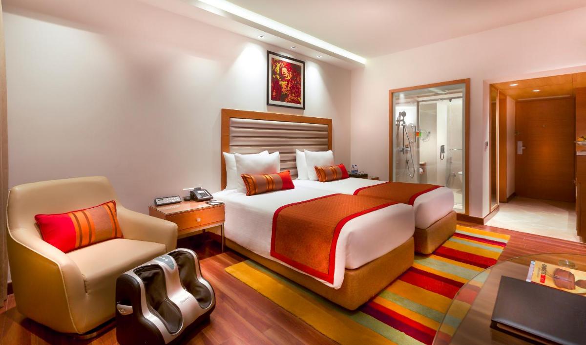 a hotel room with a bed and a chair at Grand Chennai by GRT Hotels in Chennai