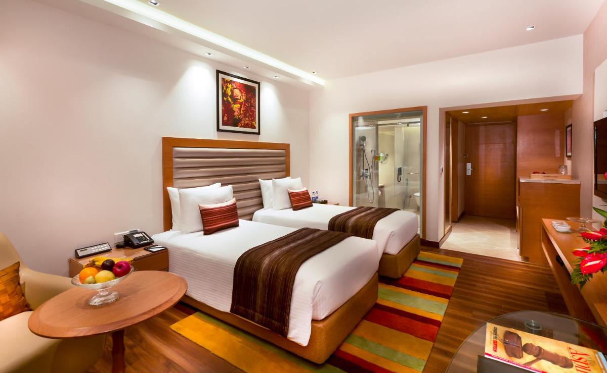 a hotel room with two beds and a bathroom at Grand Chennai by GRT Hotels in Chennai