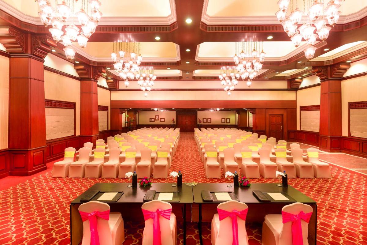 a large banquet hall with tables and chairs and chandeliers at Grand Chennai by GRT Hotels in Chennai