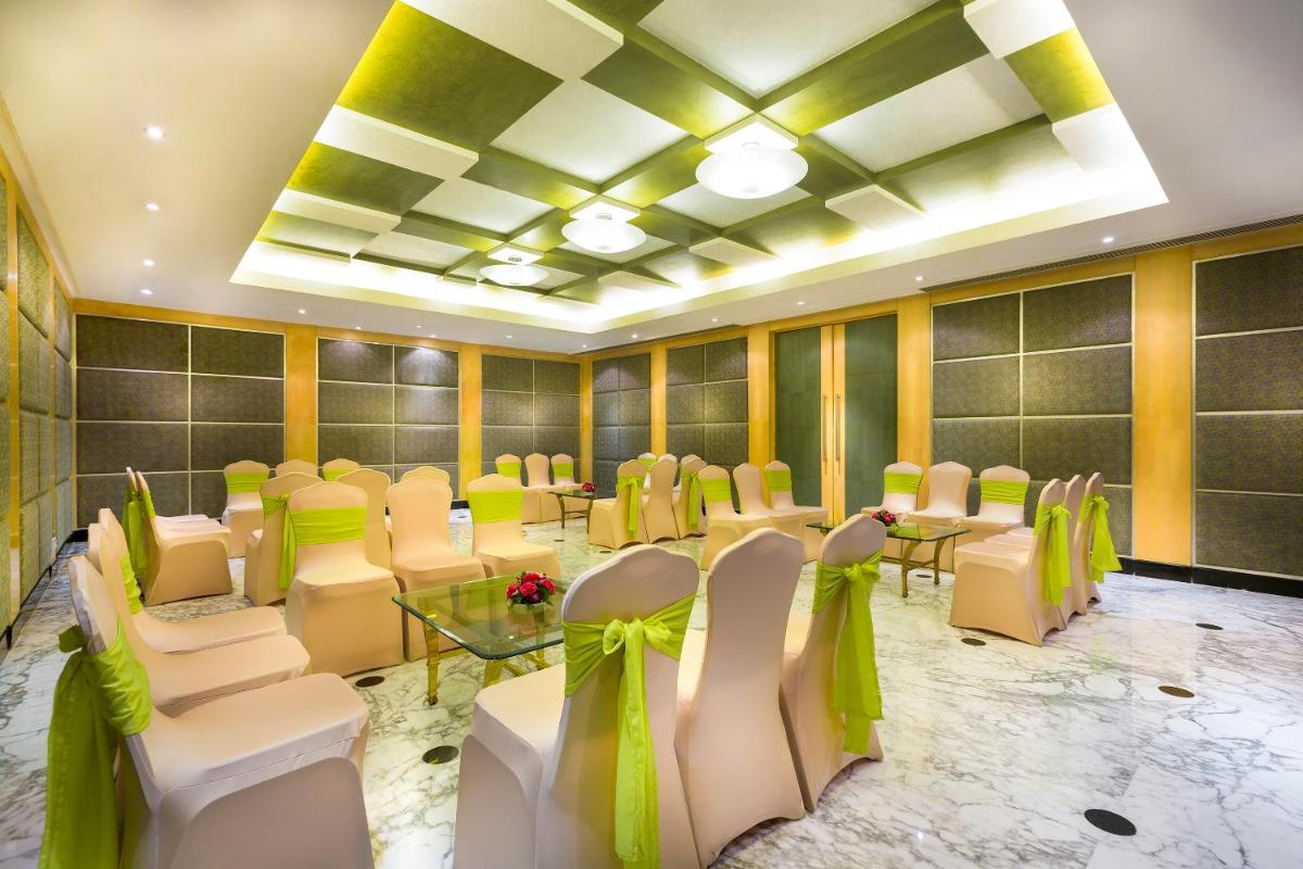 a banquet hall with white chairs and tables and green bows at Grand Chennai by GRT Hotels in Chennai