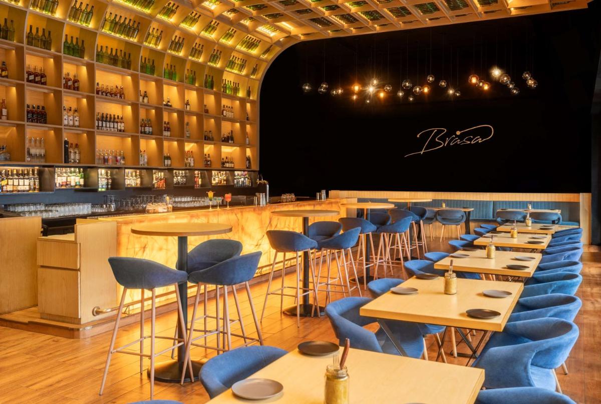 a restaurant with blue chairs and tables and a bar at Radisson Blu Hotel Chennai City Centre in Chennai a restaurant with blue chairs and tables and a bar at Radisson Blu Hotel Chennai City Centre in Chennai