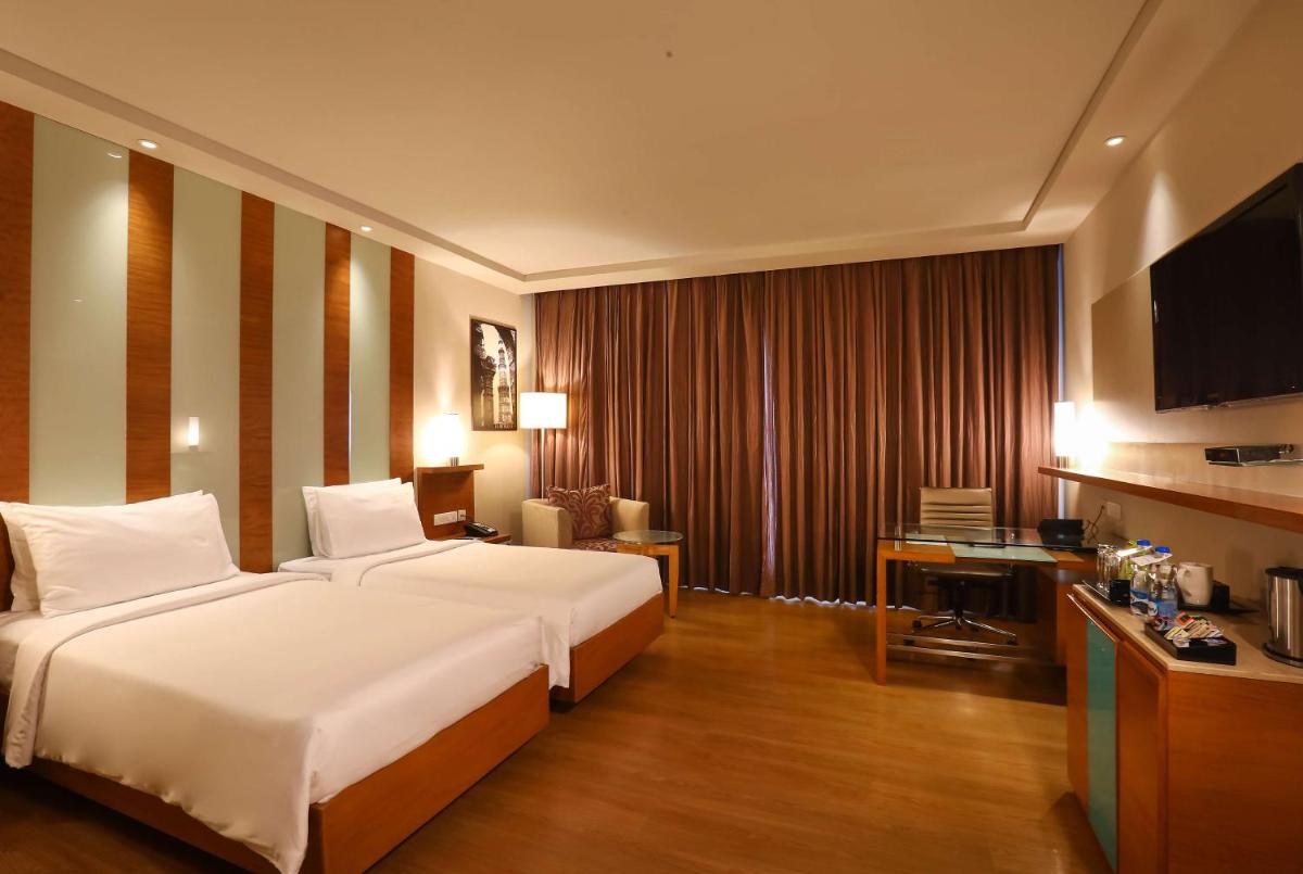 a hotel room with a large bed and a desk at Radisson Blu Hotel Chennai City Centre in Chennai a hotel room with a large bed and a desk at Radisson Blu Hotel Chennai City Centre in Chennai