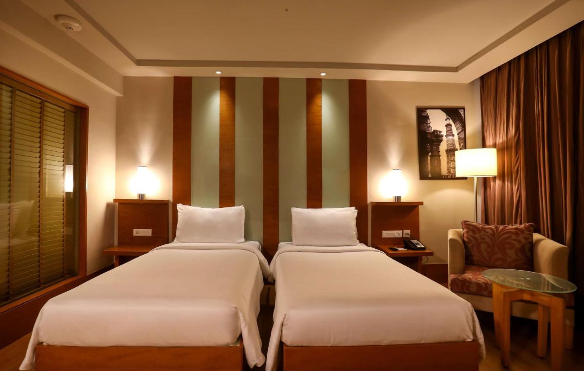 a hotel room with two beds and a chair at Radisson Blu Hotel Chennai City Centre in Chennai a hotel room with two beds and a chair at Radisson Blu Hotel Chennai City Centre in Chennai