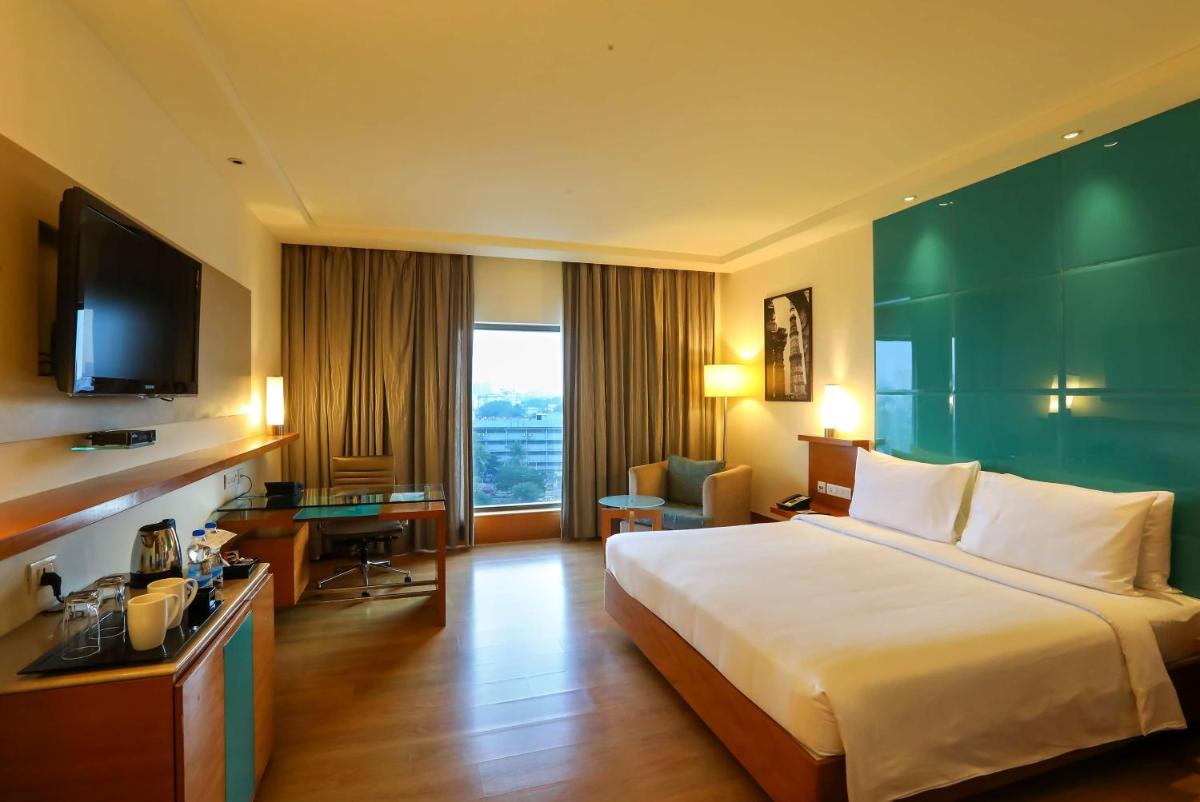 a hotel room with a large bed and a television at Radisson Blu Hotel Chennai City Centre in Chennai a hotel room with a large bed and a television at Radisson Blu Hotel Chennai City Centre in Chennai