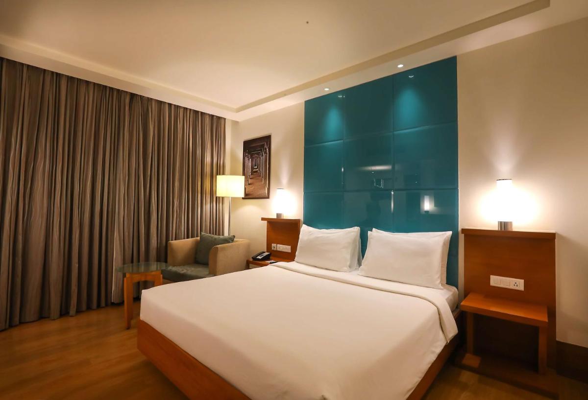 a hotel room with a large bed and a chair at Radisson Blu Hotel Chennai City Centre in Chennai a hotel room with a large bed and a chair at Radisson Blu Hotel Chennai City Centre in Chennai