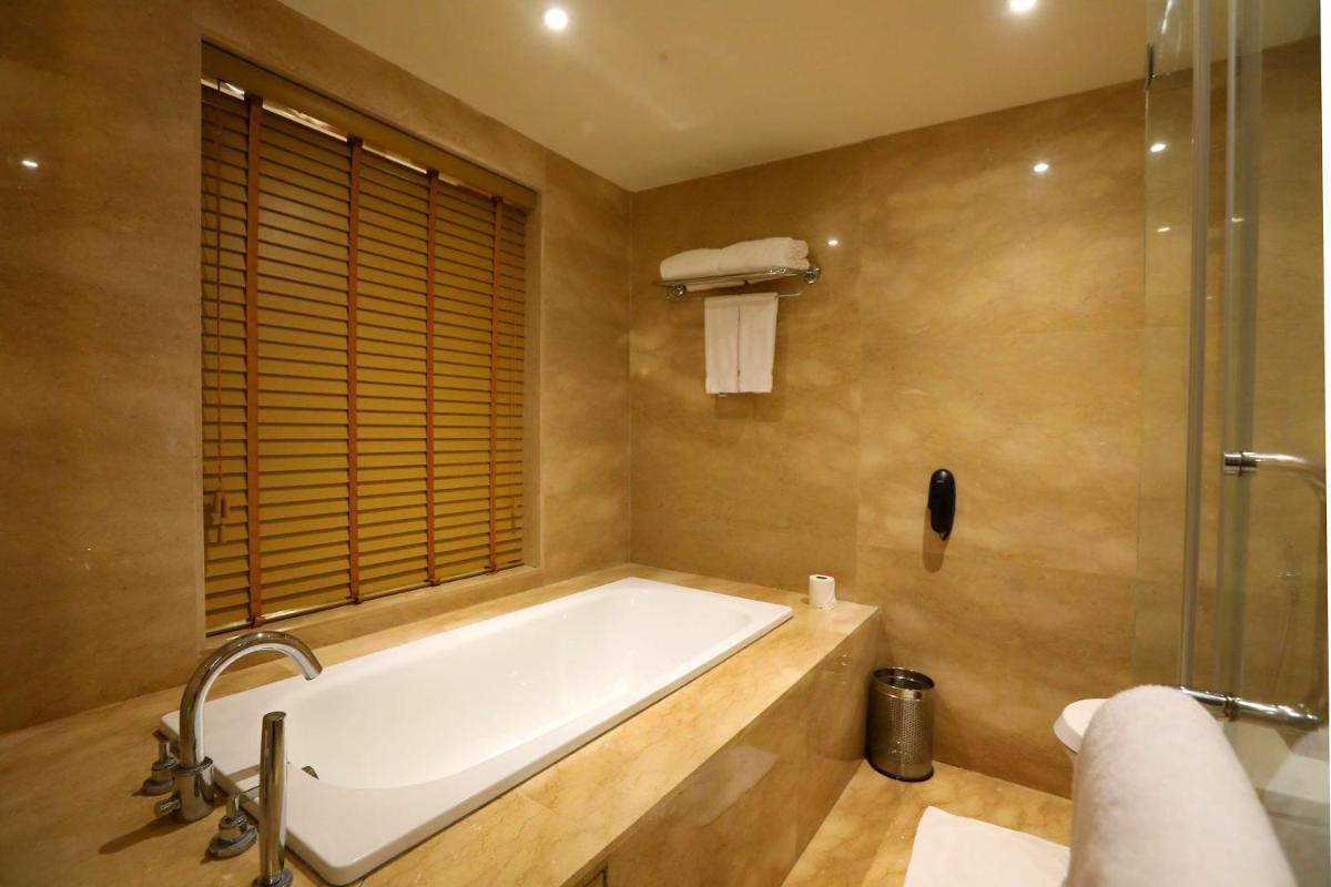 a bathroom with a bath tub and a shower at Radisson Blu Hotel Chennai City Centre in Chennai a bathroom with a bath tub and a shower at Radisson Blu Hotel Chennai City Centre in Chennai