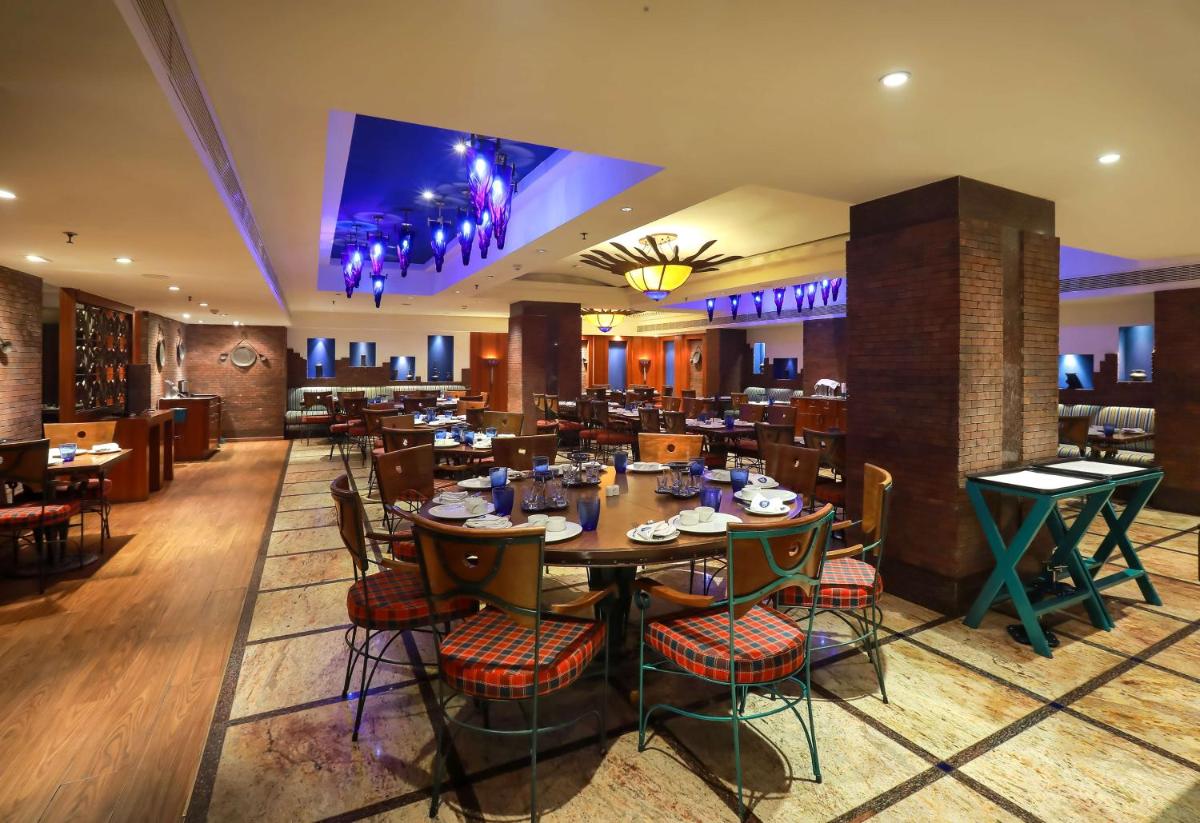 a dining room with tables and chairs in a restaurant at Radisson Blu Hotel Chennai City Centre in Chennai a dining room with tables and chairs in a restaurant at Radisson Blu Hotel Chennai City Centre in Chennai