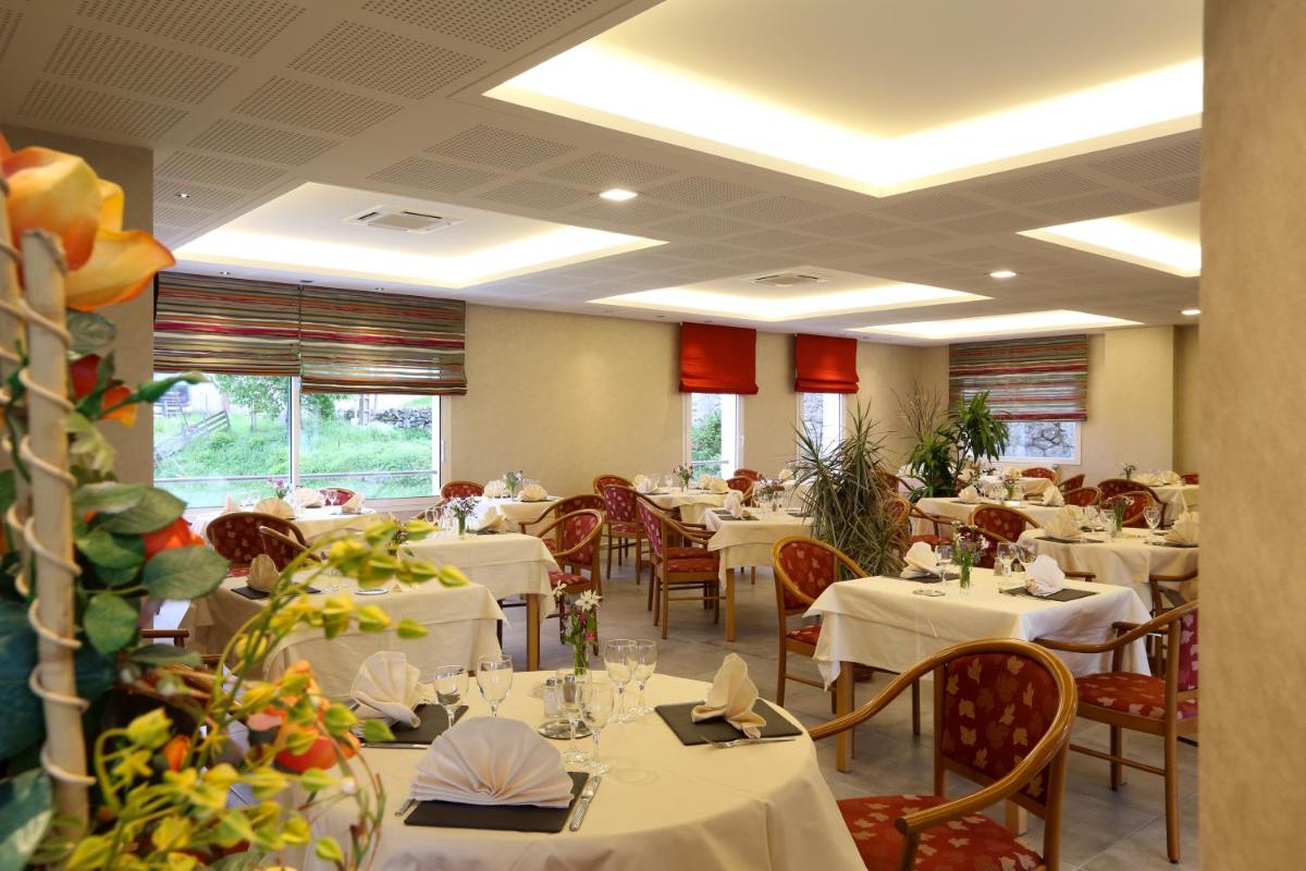 un restaurant avec tables et chaises et nappes blanches dans l'établissement Logis Hotel Spa Restaurant Le Provence, à Lanarce