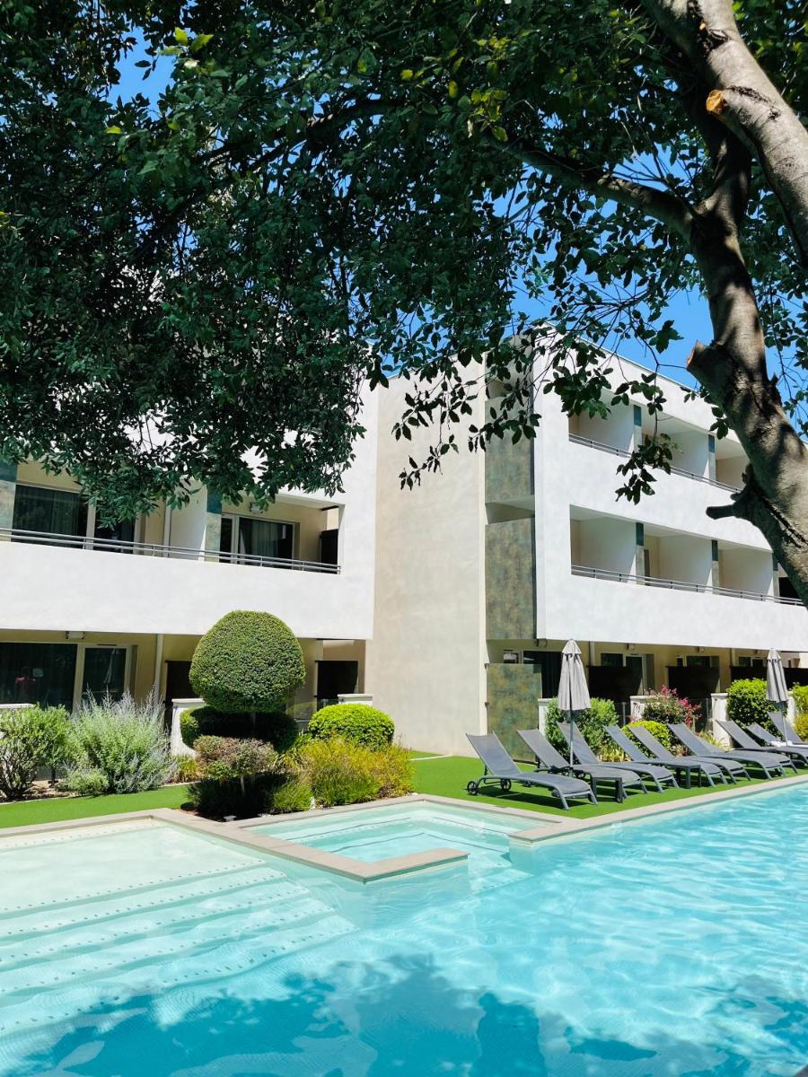 un hôtel avec piscine et chaises longues et un bâtiment dans l'établissement Forme-hotel & Spa Montpellier Sud-Est - Parc Expositions - Arena, à Mauguio