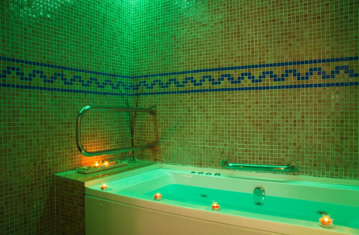 y baño de azulejos verdes con bañera verde. en Balneario Caldas de Luna, en Caldas de Luna