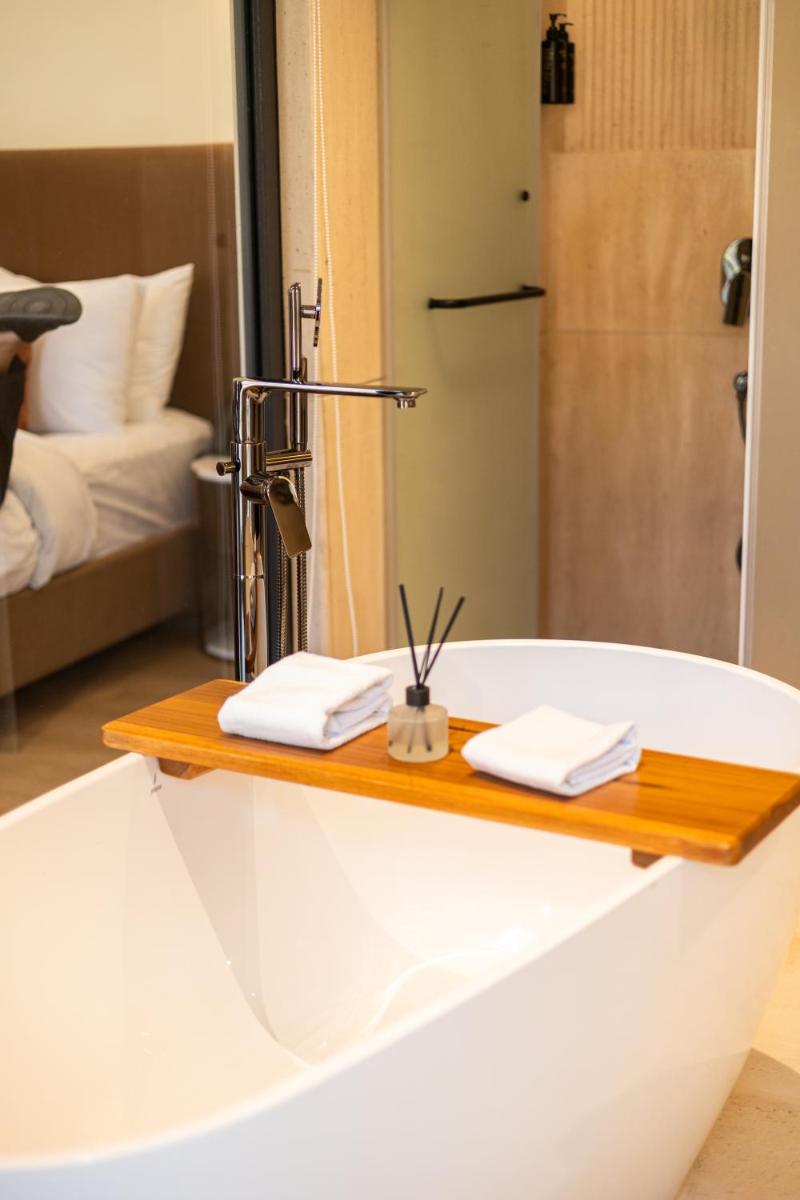 a bathroom with a bath tub with a mirror at Antalya By Divine Ganga Cottage in Rishīkesh