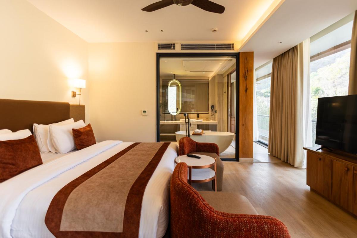 a hotel room with a bed and a tub and a television at Antalya By Divine Ganga Cottage in Rishīkesh