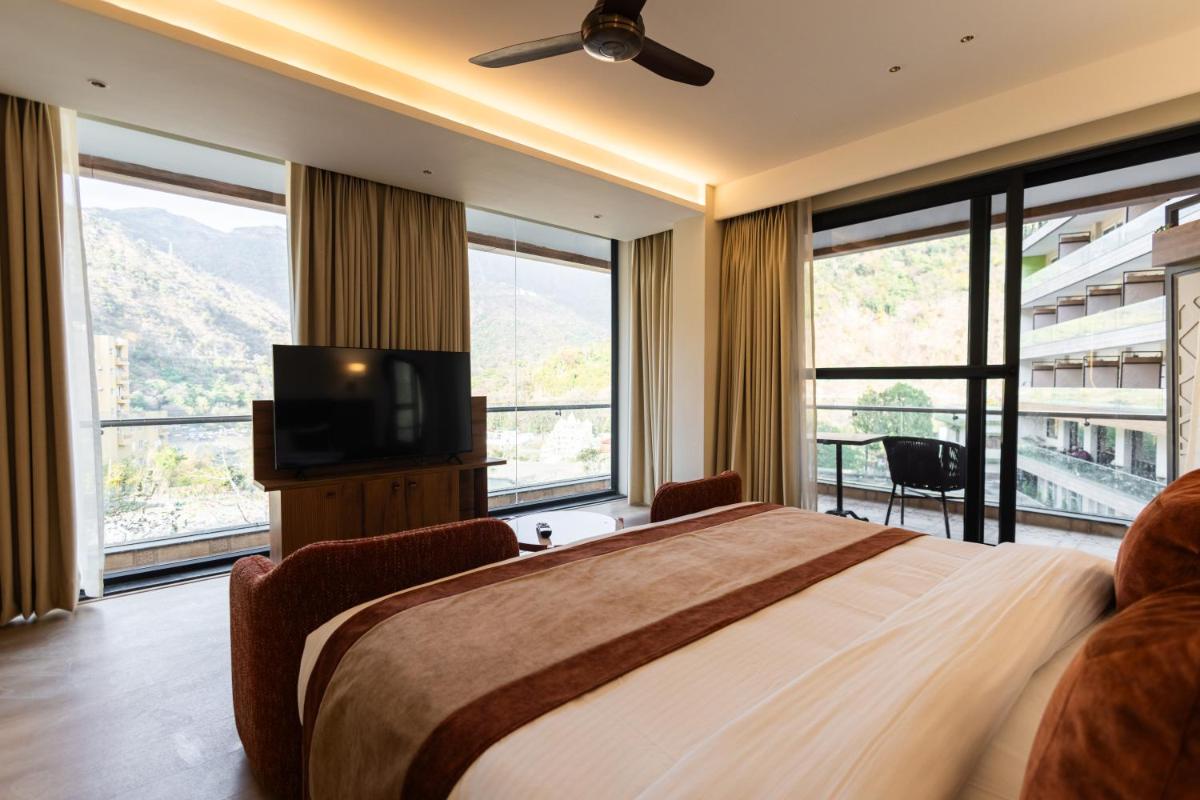 a bedroom with a large bed and large windows at Antalya By Divine Ganga Cottage in Rishīkesh