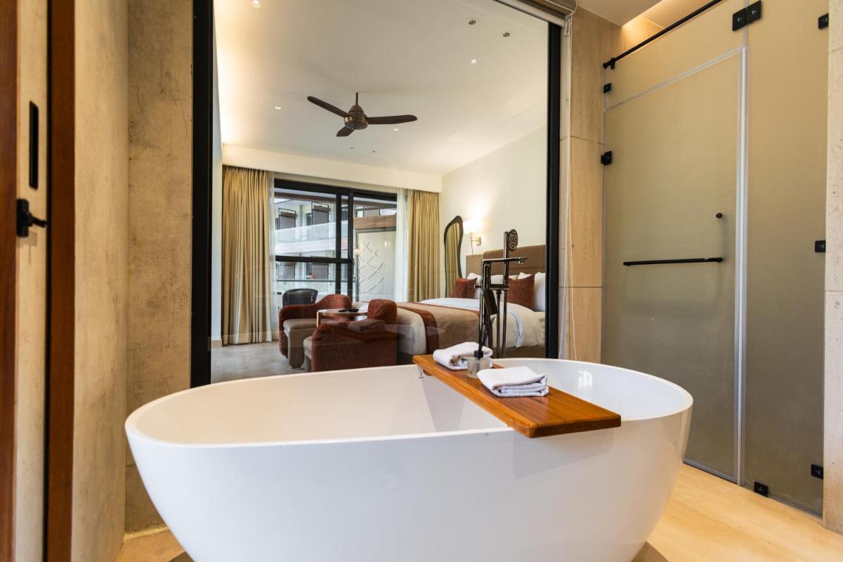 a bathroom with a white tub and a living room at Antalya By Divine Ganga Cottage in Rishīkesh