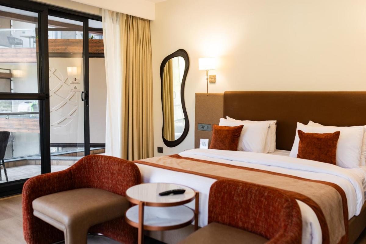 a hotel room with a bed and a chair at Antalya By Divine Ganga Cottage in Rishīkesh