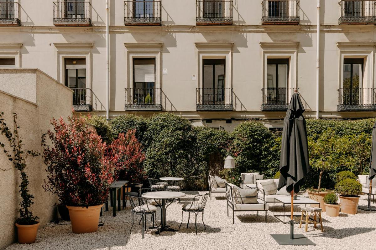 Un patio con mesas y sillas y una sombrilla. en Hotel Único Madrid, Small Luxury Hotels, en Madrid