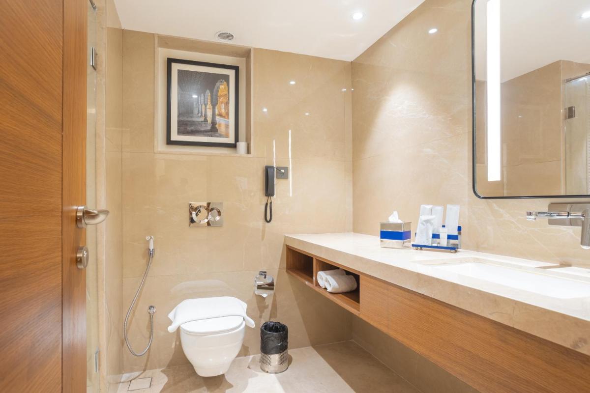 a bathroom with a toilet and a sink and a mirror at Golden Tulip Jaipur in Jaipur