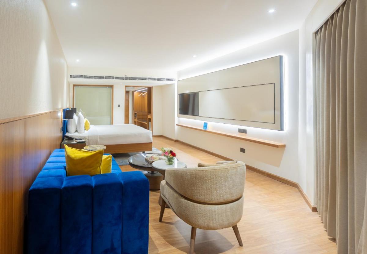 a hotel room with a bed and a living room at Golden Tulip Jaipur in Jaipur