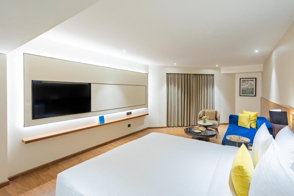 a hotel room with a bed and a flat screen tv at Golden Tulip Jaipur in Jaipur