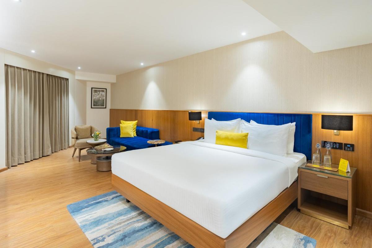a hotel room with a large bed and a chair at Golden Tulip Jaipur in Jaipur
