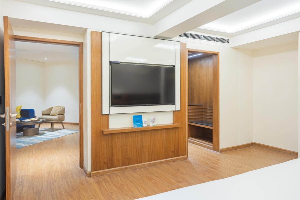 a living room with a flat screen tv on a wall at Golden Tulip Jaipur in Jaipur