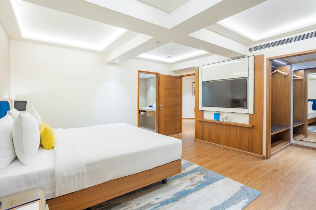a bedroom with a bed and a flat screen tv at Golden Tulip Jaipur in Jaipur