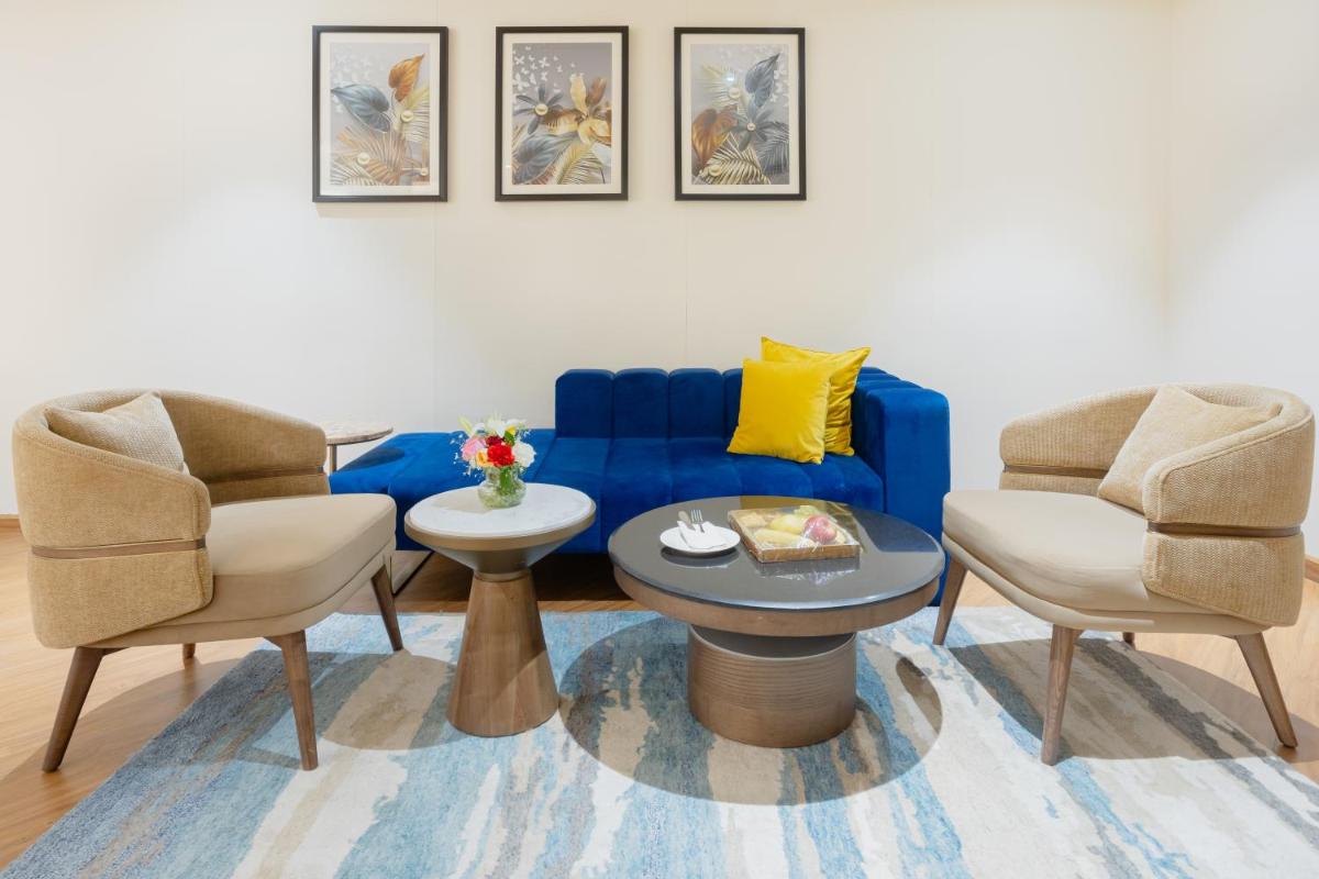 a living room with a blue couch and two chairs at Golden Tulip Jaipur in Jaipur