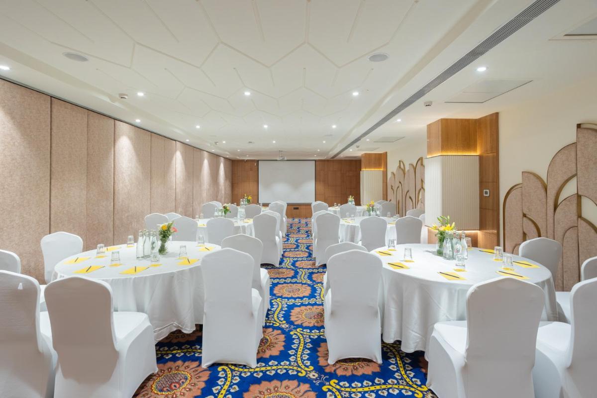 a conference room with white tables and white chairs at Golden Tulip Jaipur in Jaipur