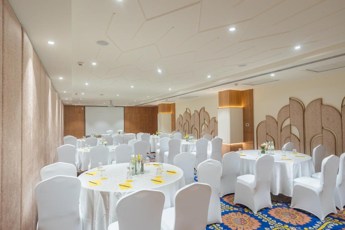 a banquet hall with white tables and white chairs at Golden Tulip Jaipur in Jaipur