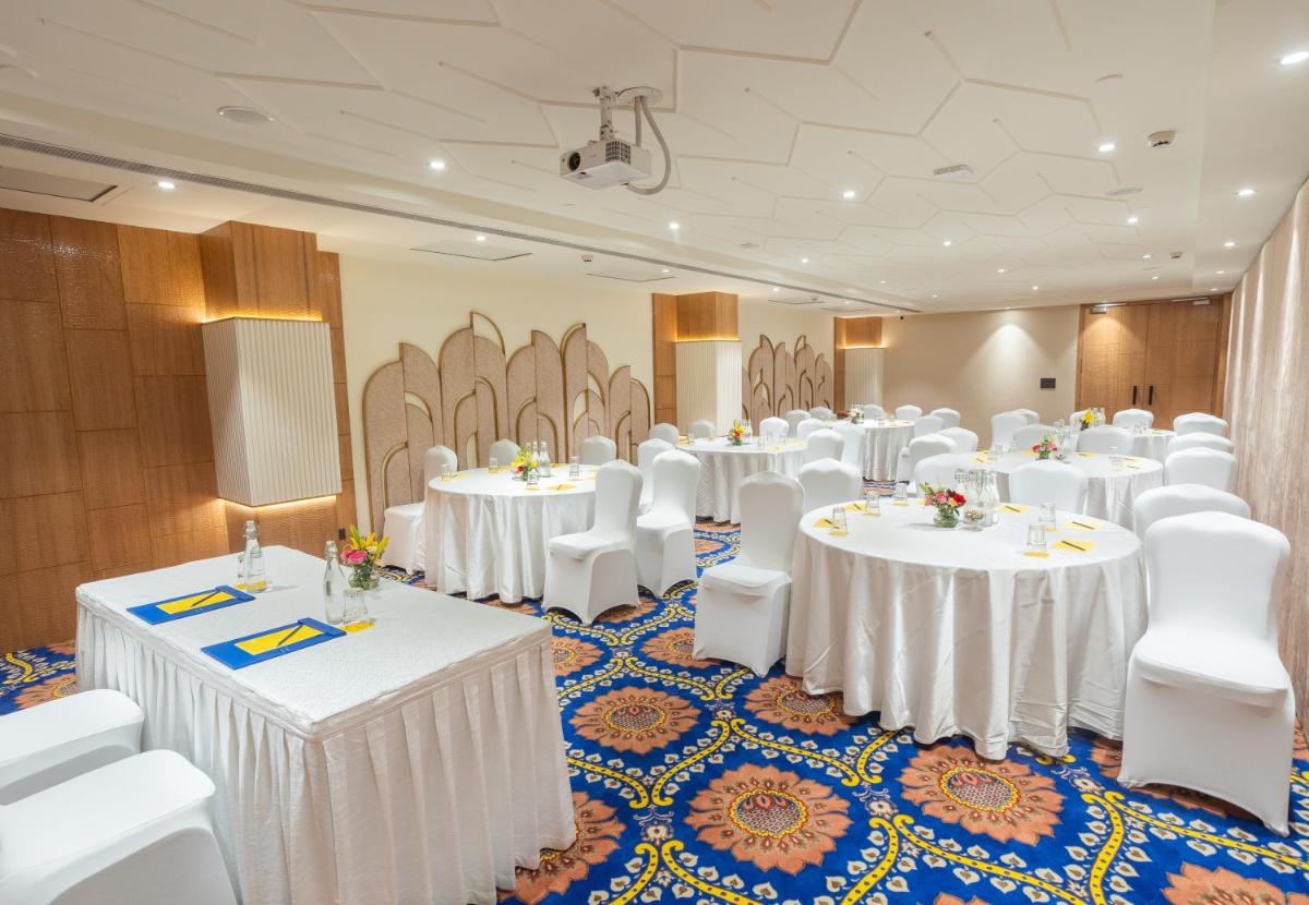 a banquet hall with white tables and white chairs at Golden Tulip Jaipur in Jaipur