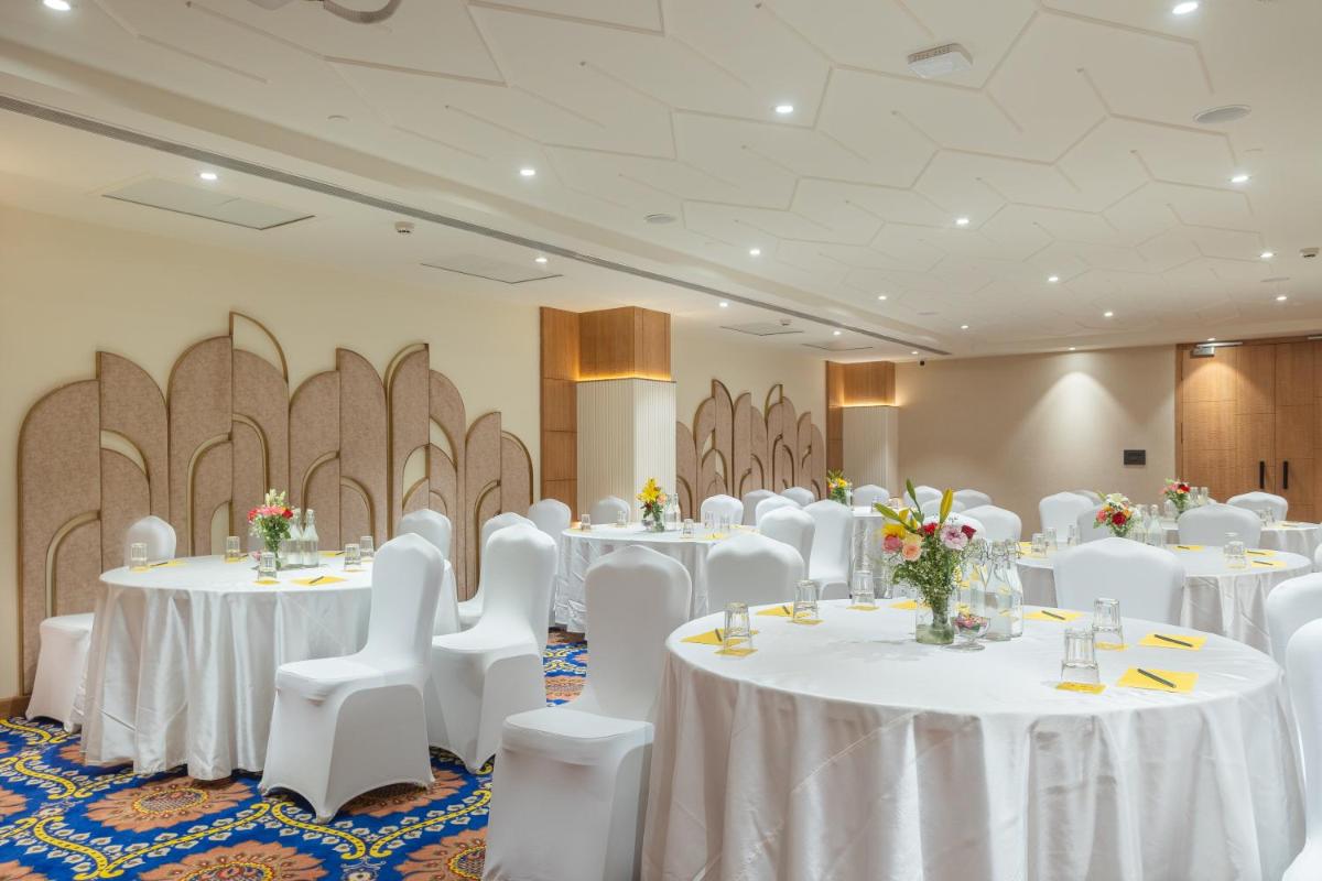 a banquet hall with white tables and white chairs at Golden Tulip Jaipur in Jaipur