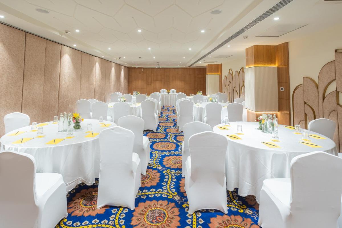 a conference room with white tables and white chairs at Golden Tulip Jaipur in Jaipur